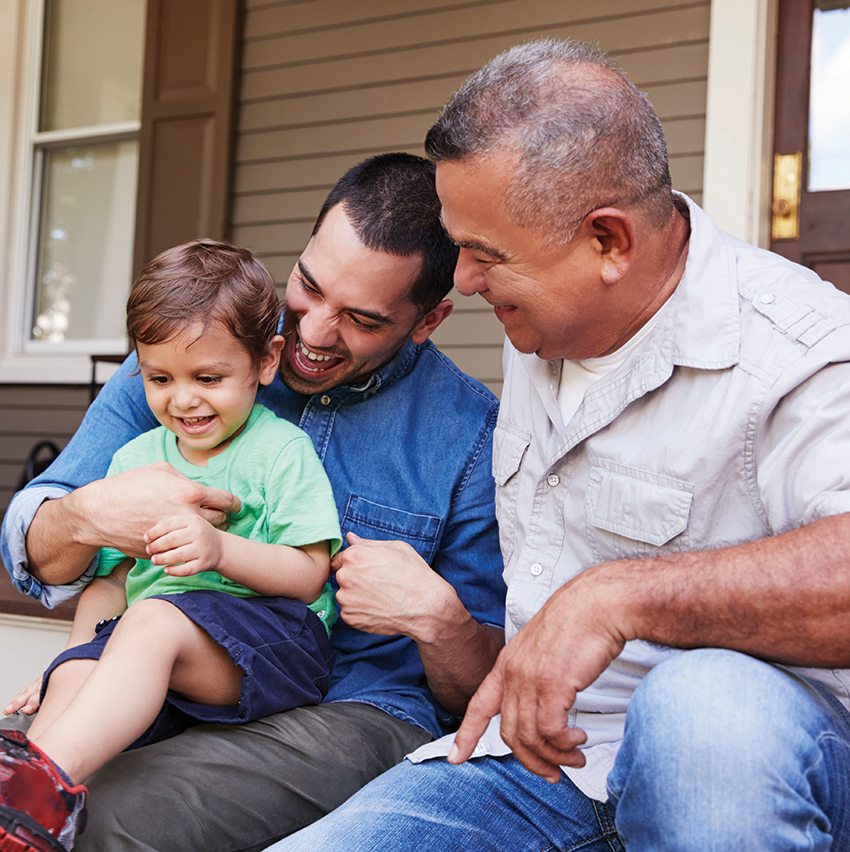 Male Multi Generation Family Sitting On Steps in Front Of House